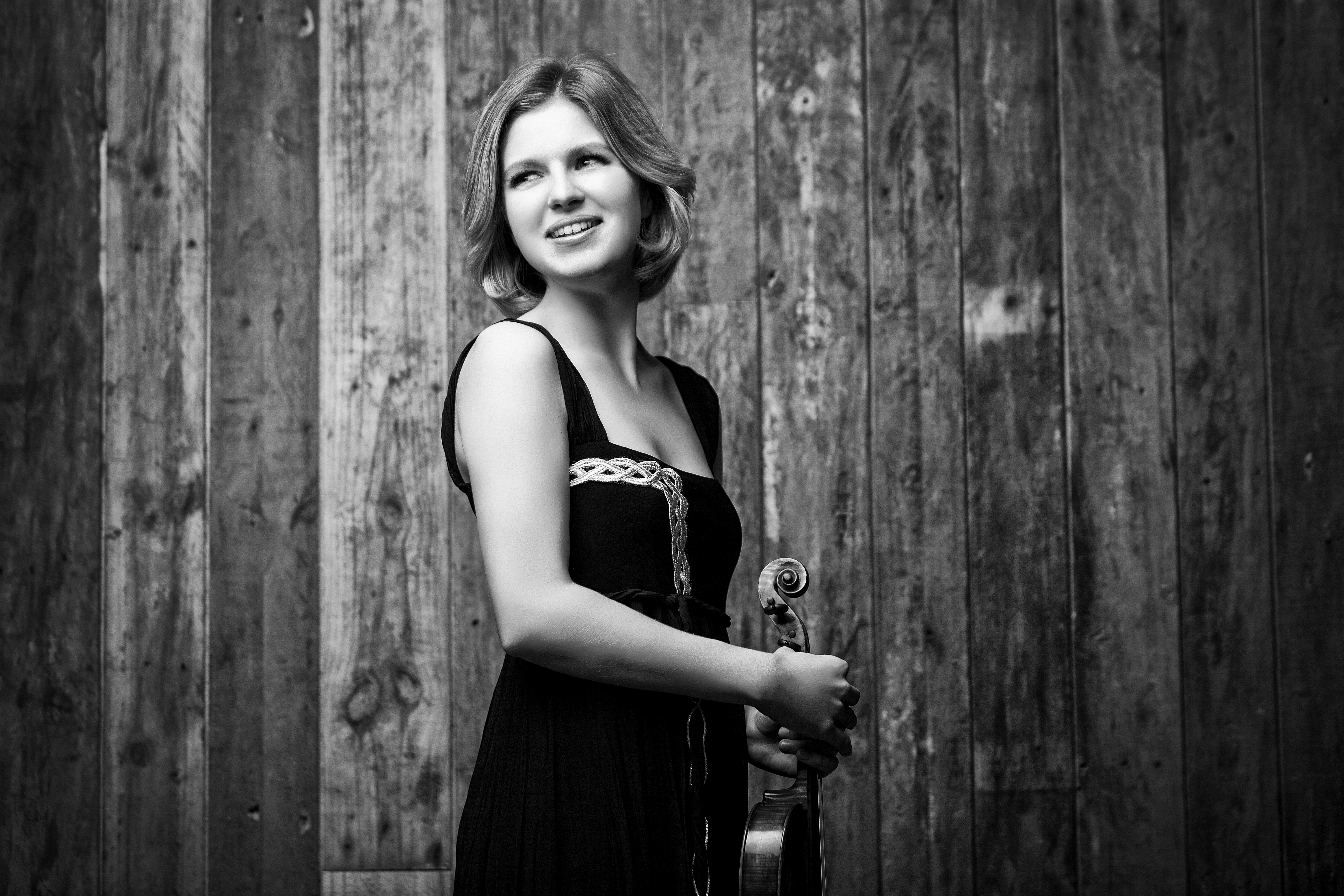 Cornelia Löscher vor einer Holzwand mit Violine in der Hand